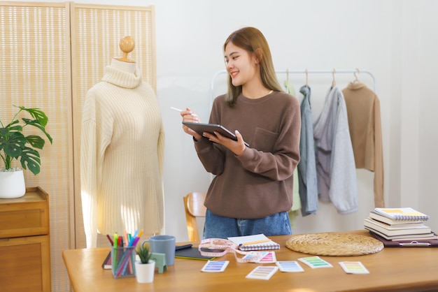 Fashion design concept Fashion designer holding tablet to checkup sweater before sending customer