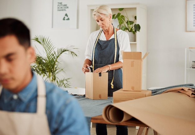 Fashion design and style with a tailor seamstress or creative designer packing boxes for shipment and delivery Female stylist preparing a box to complete an order in her studio or workshop