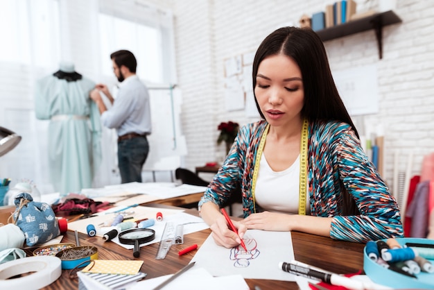 Fashion designer drawing model on paper.