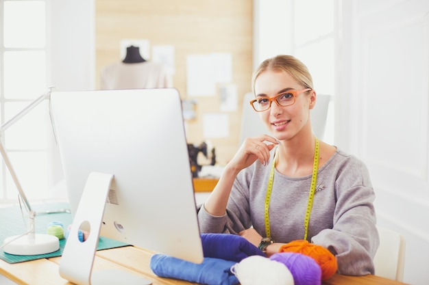 Fashion designer woman working in studio sitting at thhe desk