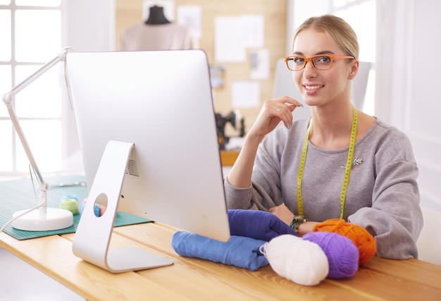 Fashion designer woman working in studio sitting at thhe desk