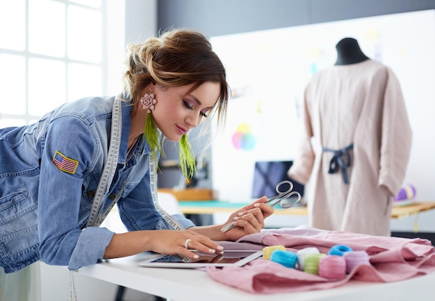 Photo fashion designer woman working with ipad on her designs in the studio