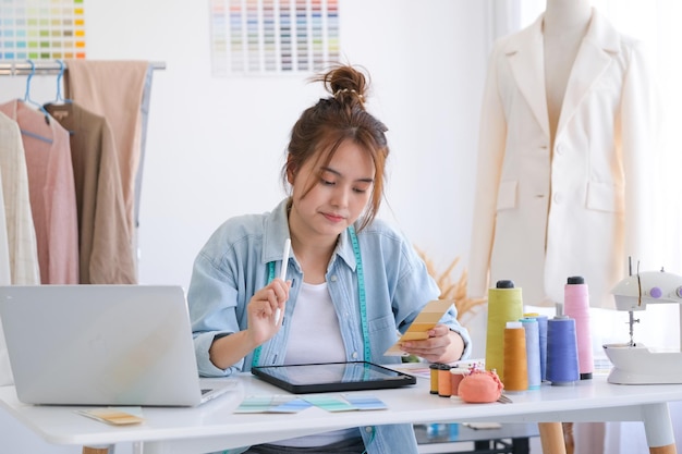 Fashion designer working in studio, cutting drawing, sewing dress