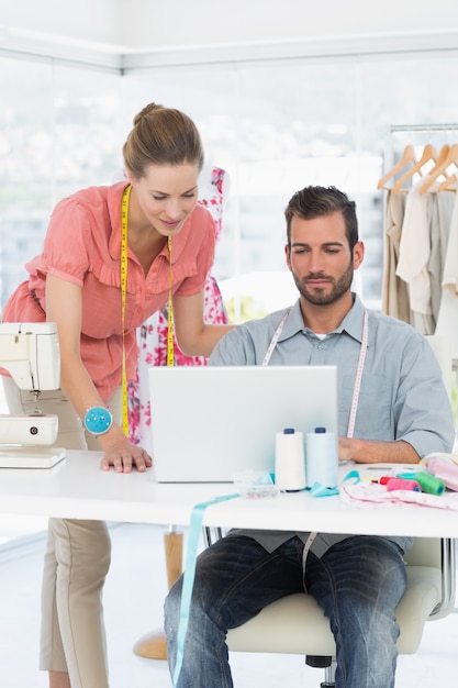 Fashion designers using laptop in bright studio