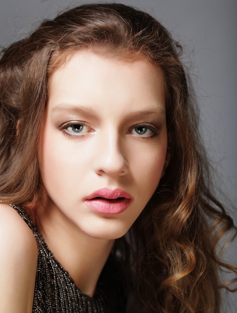 Fashion girl model posing on gray background in the studio.