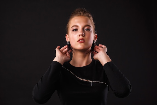 Fashion glamorous portrait of a girl in black dress on dark background Elegant hairstyle bright makeup and lip color