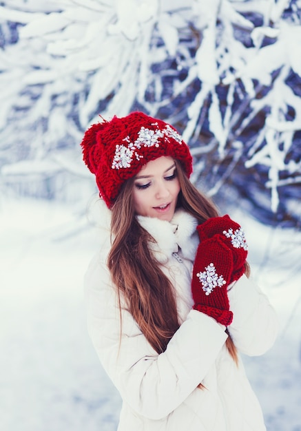 Fashion happy woman in knitted red hat having fun in winter forest