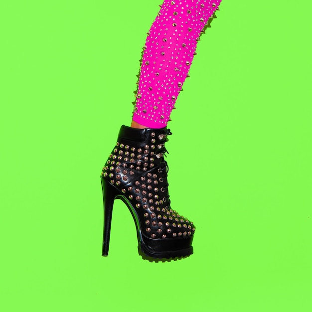 Fashion leg in heel party boots on green minimal background Stylish clubbing mood