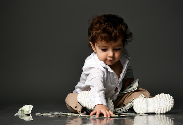 Fashion little baby boss and money Small toddler child playing counting cash banknote currency Isolated portrait isolated shot on gray studio background Children allowance and finance