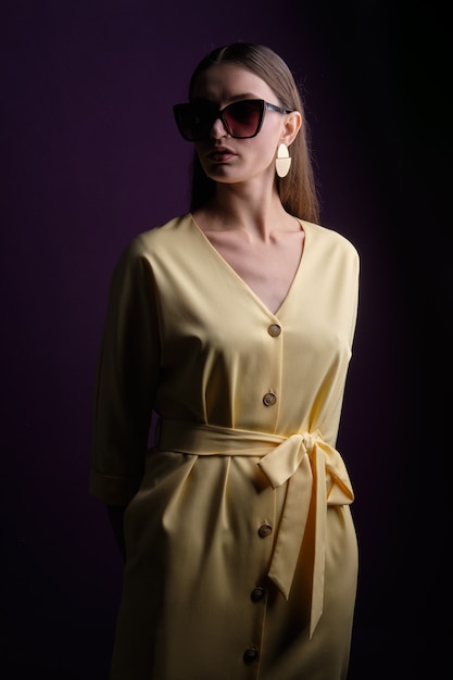 Fashion model in big sunglasses wearing yellow dress with buttons