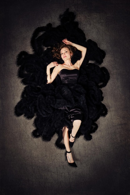 Fashion model in a luxurious puffy black dress lying on a floor