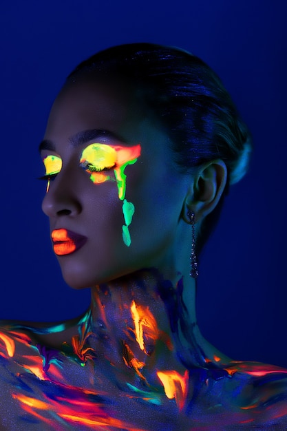 Fashion model in neon light with fluorescent paint.