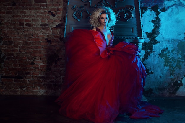 Fashion photo of young magnificent woman in red dress. Studio portrait