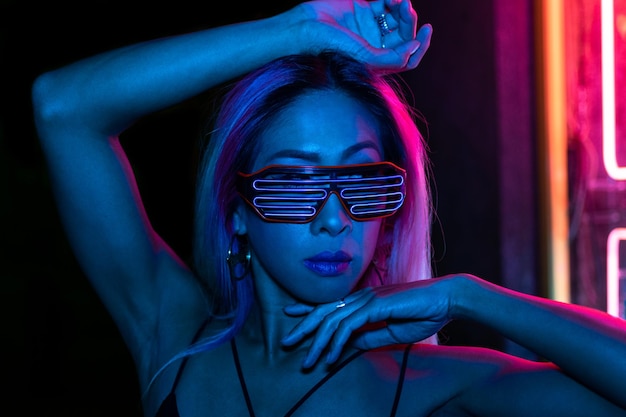 Fashion portrait of beautiful asian woman posing in colorful bright neon uv blue and red lights