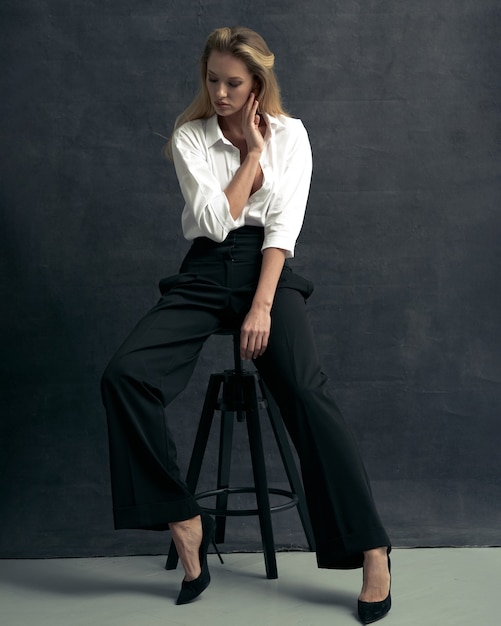 Photo fashion portrait of beautiful woman with white shirt and black pants on dark background studio