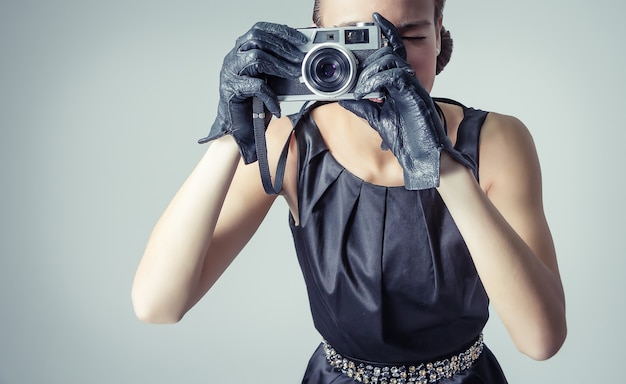 Fashion portrait of beautiful young girl in classic vintage style with an analogue photo camera