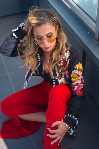 Fashion portrait of a blonde woman on a terrace sitting on the ground