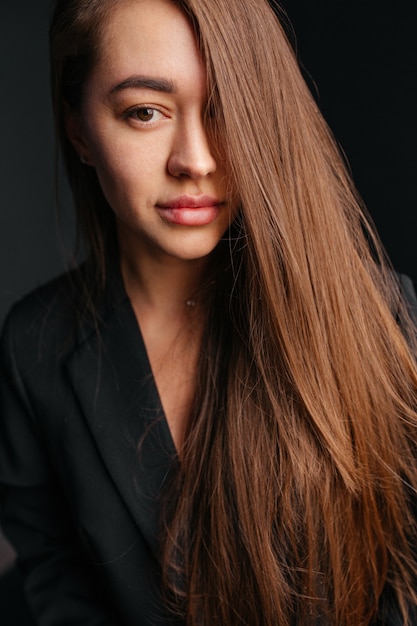 Fashion portrait of a caucasian woman with long brunette hair in a black suit jacket