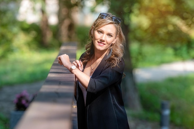 Fashion portrait of a stylish nice blonde female in sunglasses leaning on a railing of pedestrian bridge