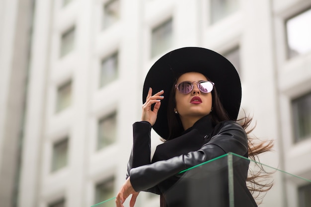 Fashion portrait of stylish woman in wide brimmed black hat and mirror sunglasses