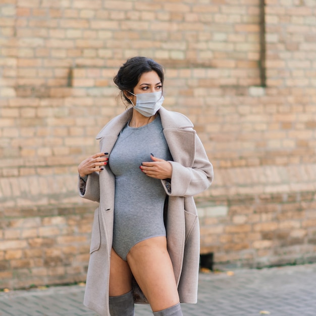 Fashion portrait of   woman in face mask and lingerie in autumn park. Pandemic, virus, coronavirus