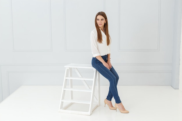 Fashion portrait of woman in jeans in light studio