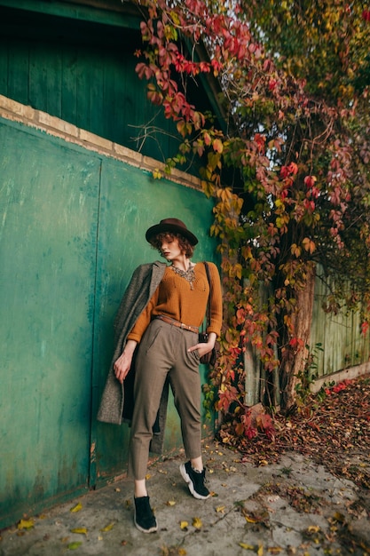 Fashion portrait of a woman in vintage clothing on a background of a country house and an ivy