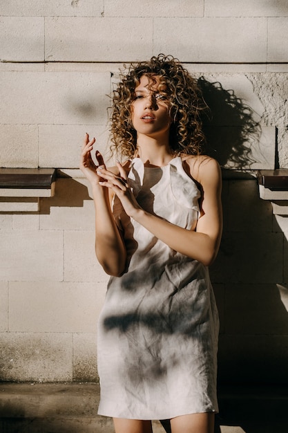 Fashion portrait of a young woman posing on a city building wall