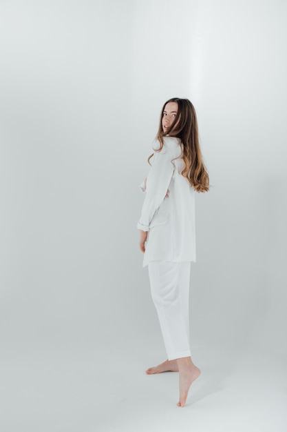 Fashion portrait of a young woman in white suit.