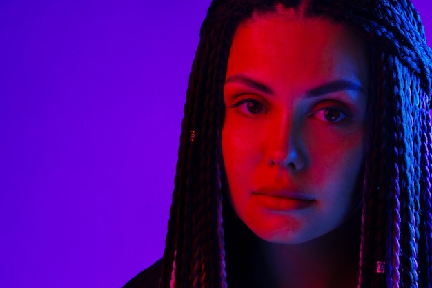 Fashion portrait of young woman with dreadlocks in neon light