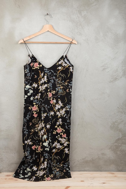 Fashion and shopping concept - beautiful dress in floral pattern on a hanger on grey background