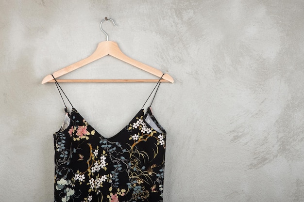 Fashion and shopping concept - beautiful dress in floral pattern on a hanger on grey background