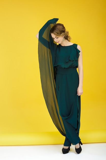 Photo fashion shot of beautiful woman in green dress on a yellow background