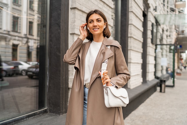 Fashion street portrait of stylish european brunette woman in leather coat posing outdoor