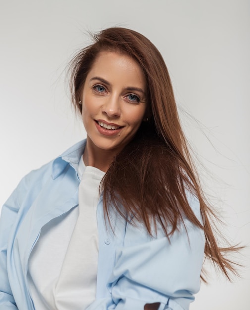 Fashion studio female portrait of a happy beautiful young girl model in fashionable clothes with a shirt on a white background