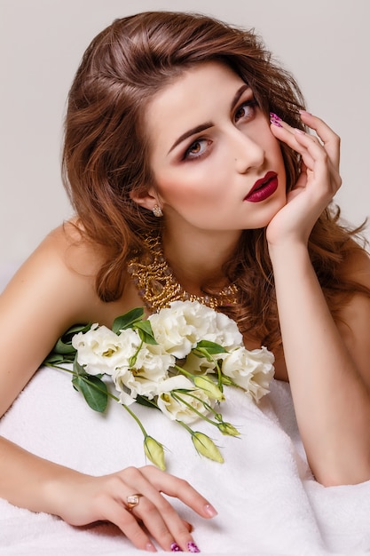 Fashion studio photo of beautiful brunette woman with bright makeup with a bouquet of purple and white eustoma