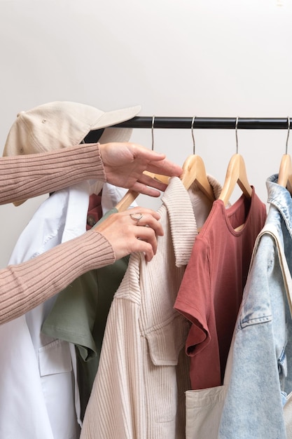 Fashion stylist chooses clothes on railing in showroom Basic womens clothes and eco bag