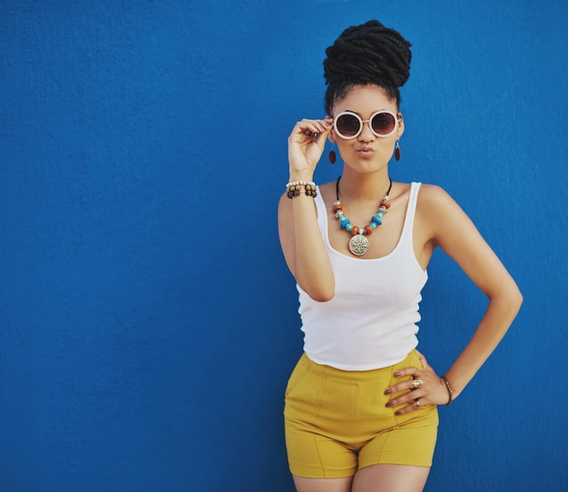 Fashion summer and black woman with sunglasses on blue background wall in city on weekend Freedom beauty and girl enjoy holiday travel and vacation in urban town with trendy clothes and cosmetics