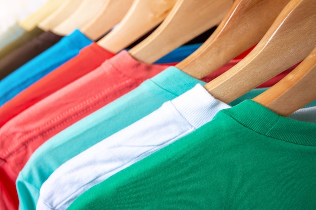 Fashion T-shirt on clothing rack - Closeup of bright colorful closet on wooden hangers in store closet.