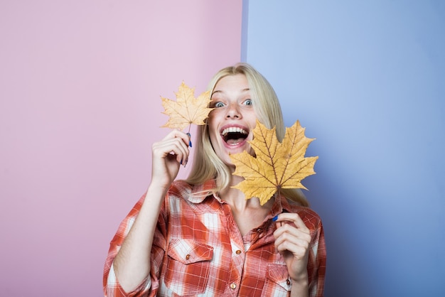 Fashion trends for fall surprised girl in casual wear holds yellow leaves autumn girl with golden