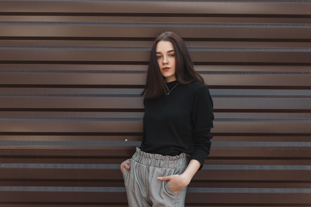 Fashion woman in stylish clothes near a metal wall