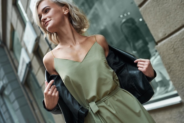 Photo fashion young stylish woman walking on the city street taking off jeans jacket smiling joyful