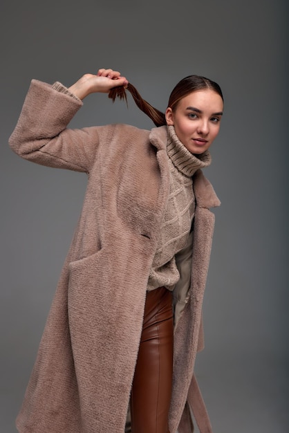 Fashion young woman in a faux fur coat on a gray background