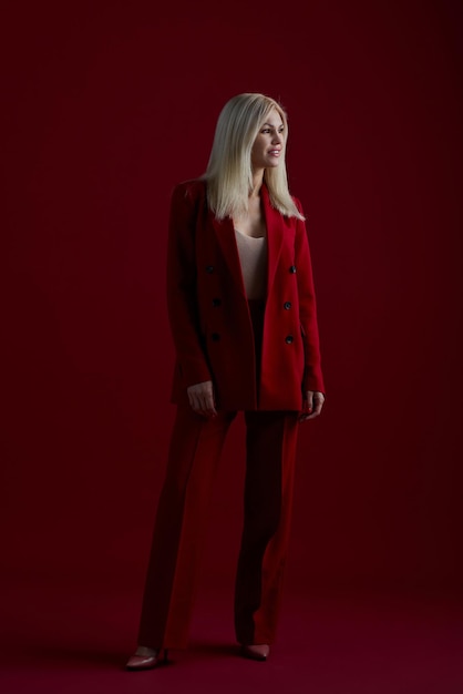 Fashion young woman in red suit Red background