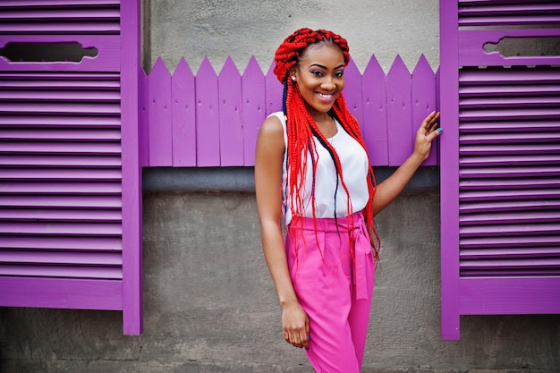 Fashionable african american girl at pink pants and red dreads posed outdoor