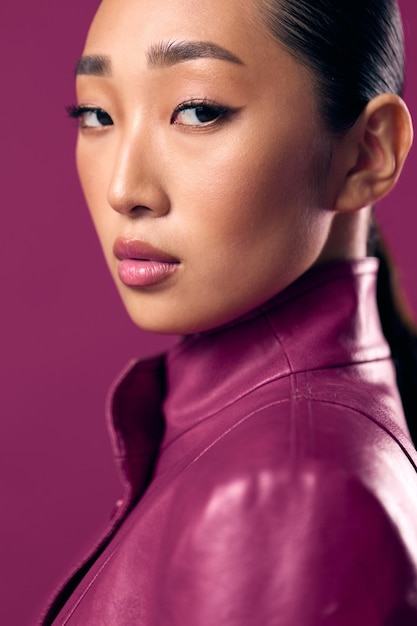 Photo fashionable asian brunette woman in a purple leather jacket with her hair tied back in a ponytail