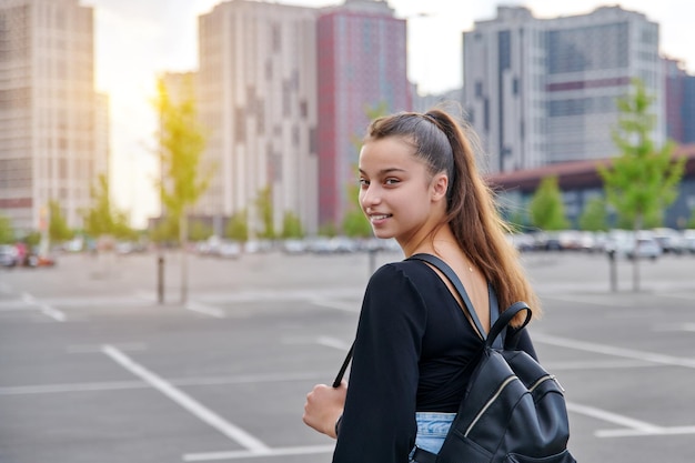 Fashionable beautiful smiling teenage girl in shorts with backpack looking at the camera