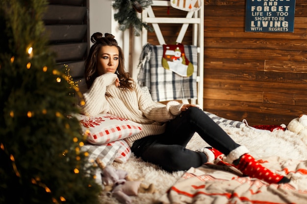 Fashionable beautiful young woman in a knitted vintage sweater with red Christmas socks lies on the bed