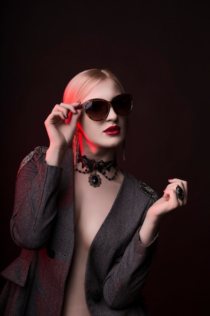 Fashionable blonde lady in glasses with bright makeup at studio