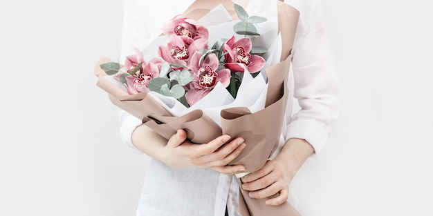 Fashionable bouquet with red orchids in hands of woman